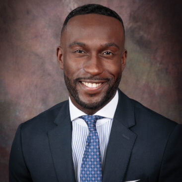 Professional portrait of a smiling man in a suit and tie.